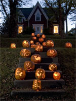 Jo-Ann's carved pumpkins line the stairs of a home in Mahone Bay in the evening.